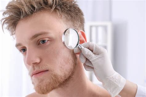 Dermatologist Examining Patient With Magnifying Glass In Clinic Stock