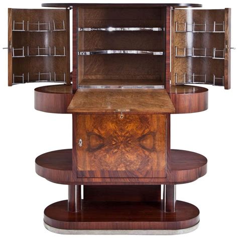 This french art deco mirrored bar cabinet is raised upon a pedestal base and features two doors visually linked by an octagonal insert etched with figural declaration: Vintage Art Deco Bar Cabinet For Sale at 1stdibs