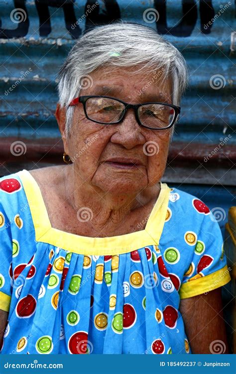 a mature filipino woman rests on a sidewalk and poses for the camera editorial photography