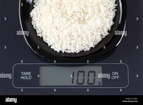 Weißer Reis in einer schwarzen Platte auf digitale Waage anzeigen 100