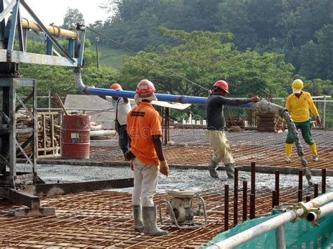 Group Of Construction Workers Pouring Wet Concrete Using The Concrete