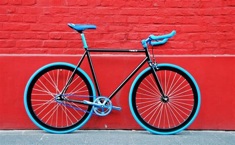 A Black And Blue Bicycle Parked In Front Of A Red Brick Wall