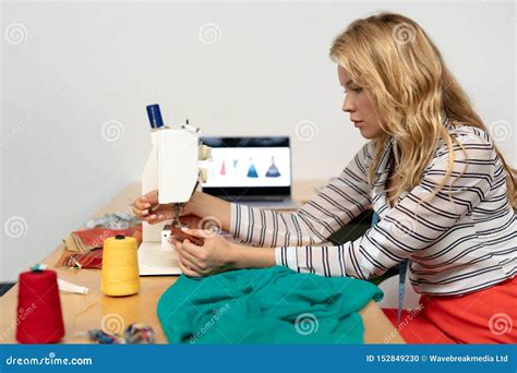 Female Fashion Designer Using Sewing Machine On A Table Stock Photo
