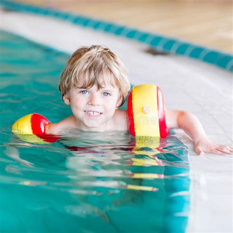 Little Kid Boy With Swimmies Learning To Swim In An Indoor Pool Stock