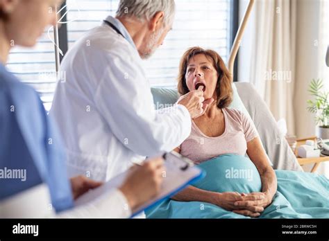 Senior Male Doctor Examining A Woman Patient In Hospital Stock Photo