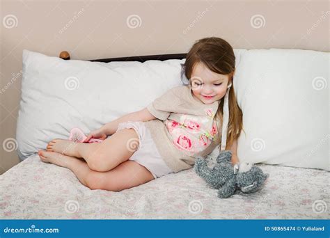 Маленькая девочка в кровати играя со своим плюшевым медвежонком Стоковое Фото изображение