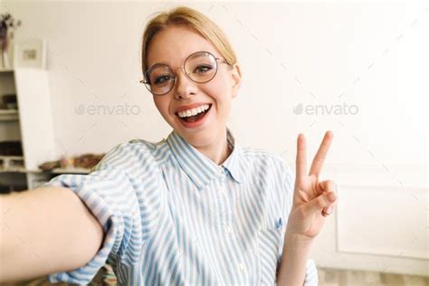 photo of joyful blonde woman showing peace sign while taking selfie pose reference photo pose