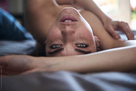 Nude Woman Lying On Bed Looking At Camera By Stocksy Contributor