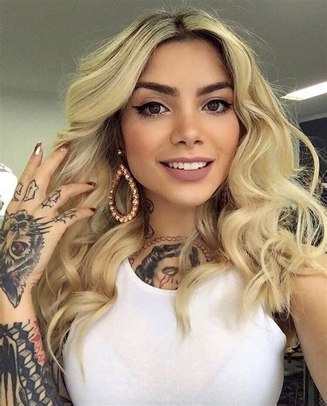 A Woman With Long Blonde Hair And Tattoos On Her Arms