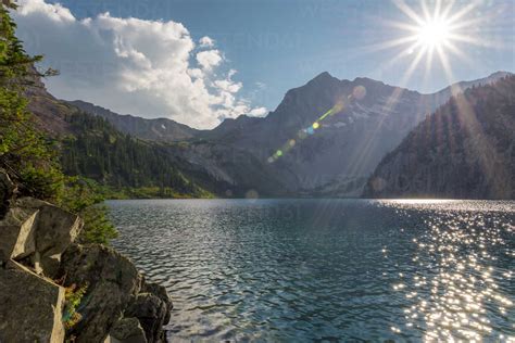 Scenic View Of Lake Against Mountains In Forest During Sunny Day Stock