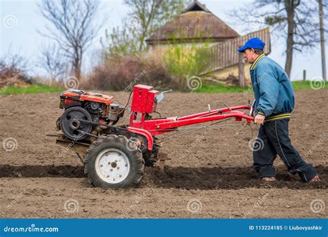 Farmer Plows The Land With A Cultivator Preparing It For Planting