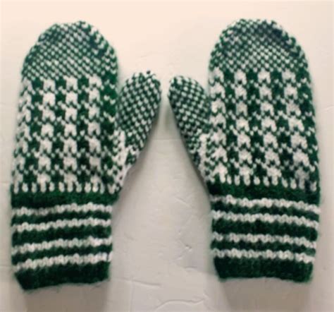 Two Green And White Mittens Sitting On Top Of Each Other