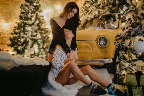 lesbian couple hugs against background of christmas decorations and retro car stock image