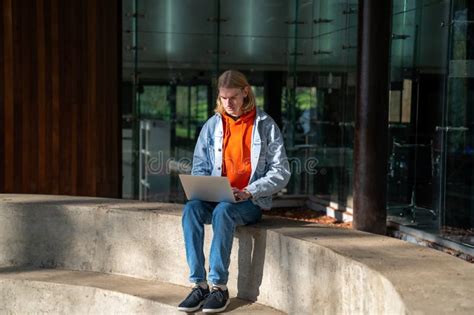 Student Guy Sitting With Laptop Against University Building Studying