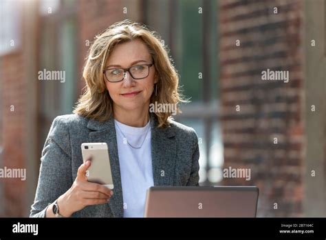 Portrait Of A Beautiful Business Woman 55 Years Old She Uses Her Mobile Phone And Laptop On