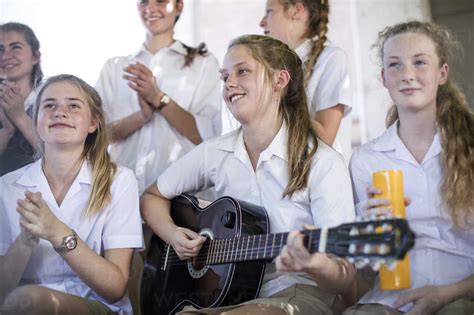 Female High School Student Playing Guitar With Group Of School Friends