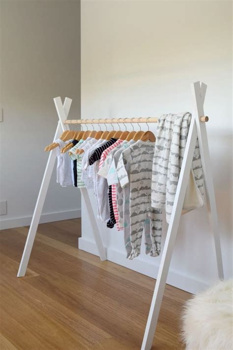 A Rack With Clothes Hanging On It Next To A White Wall And Wooden Flooring