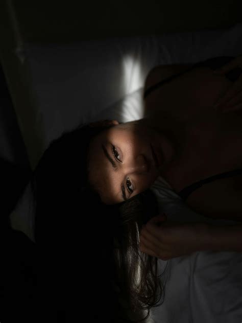 Alluring Young Lady Lying On Bed In Dark Room · Free Stock Photo