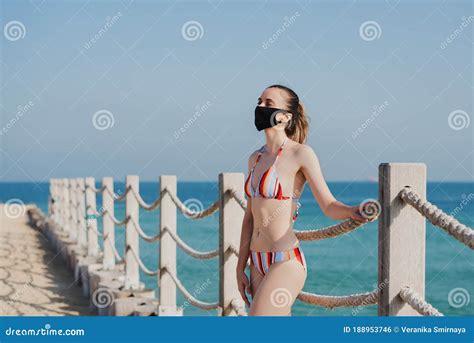 Woman In A Bikini Wearing Reusable Face Mask Standing At The Beach My