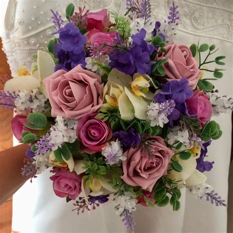 A Wedding Bouquet Featuring Artificial Ivory Purple And Pink Flowers