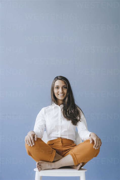 Pretty Young Woman Sitting Cross Legged On A Chair Stock Photo