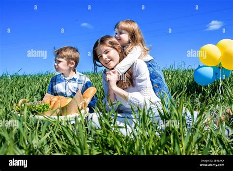 Three Happy Kids Sitting On Picnic On The Field Blue Sky Green Grass