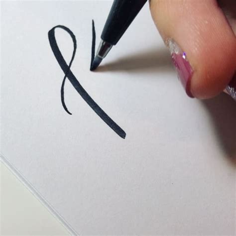 A Person Writing On Paper With A Pen
