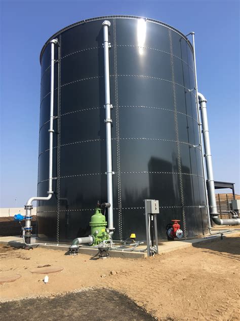 A Large Black Tank Sitting In The Middle Of A Dirt Field Next To A