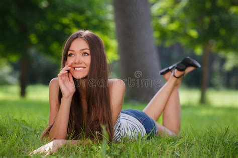 mulher de sorriso bonita que encontra se em uma grama exterior imagem de stock imagem de