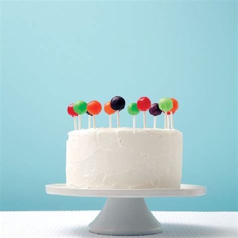 A White Cake Topped With Lots Of Colorful Candy Lollipops On Top Of It