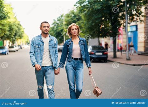 Beautiful Young Couple Holding Hands And Smiling While Walking Outdoors