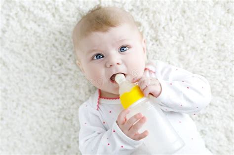 Cute Adorable Ewborn Baby Girl Holding Nursing Bottle And Drinking