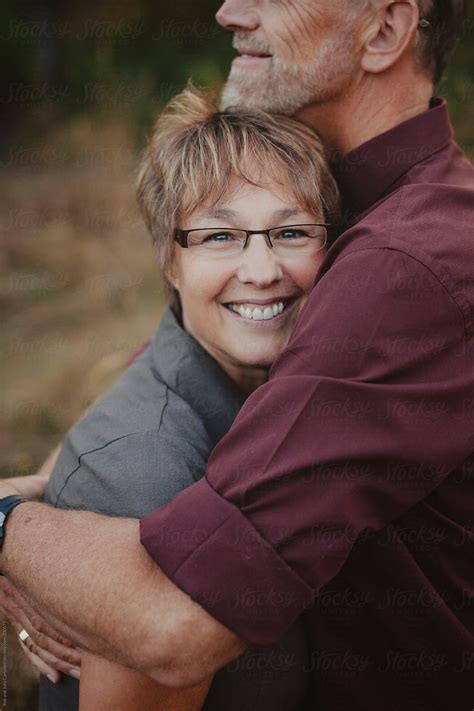 middle aged woman enjoying a hug from her husband by stocksy contributor rob and julia