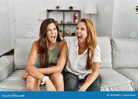 Mother And Daughter Together Sitting On The Sofa At Home Angry And Mad Screaming Frustrated And