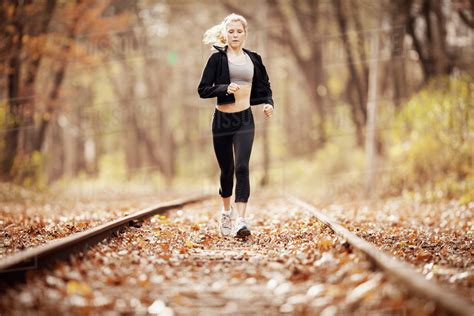 Full Length Of Woman Jogging On Railroad Track During Autumn Stock