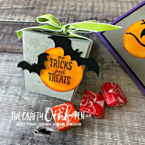 A Trick Or Treat Box With Candy In It And Two Halloween Candies Next To It