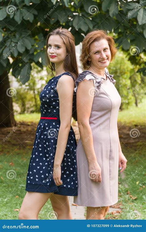 Closeup Portrait Of Adult Daughter And Mother Outdoors Pretty Brunette And Her Mom Are Looking