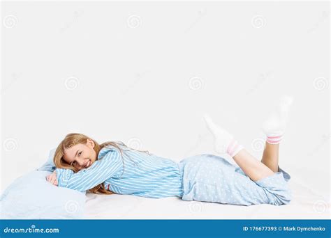 Beautiful Girl In Pajamas Lying On The Bed With Pillows In Her Hands