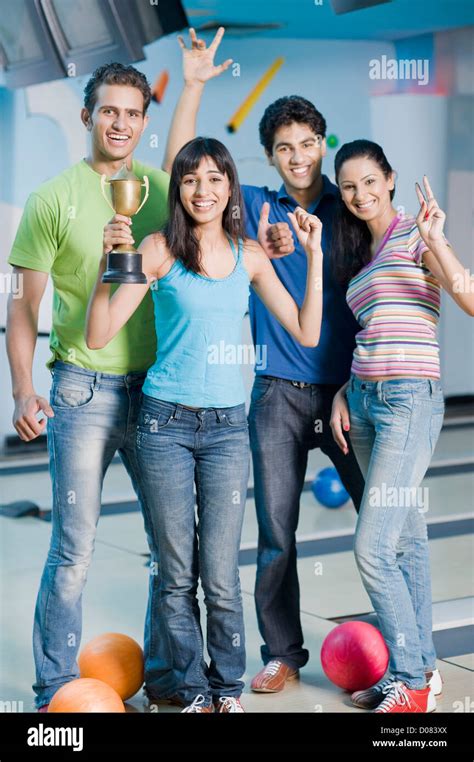 Two Young Couples With Bowling Balls And A Trophy In A Bowling Alley