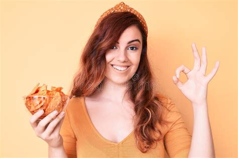 Young Beautiful Woman Holding Nachos Potato Chips Doing Ok Sign With Fingers Smiling Friendly