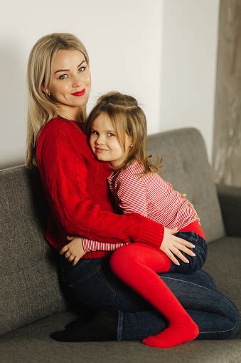 kleines mädchen in roten strumpfhosen mit mama in rotem pullover glückliche familie zu hause