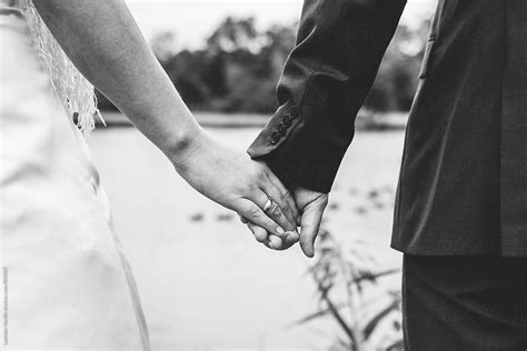 Detail Of Bride And Groom Holding Hands With Wedding Ring In Black And