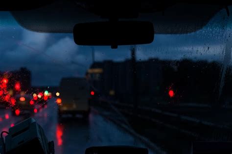 Premium Photo Car Front Window With Raindrops And Road With Cars At Night