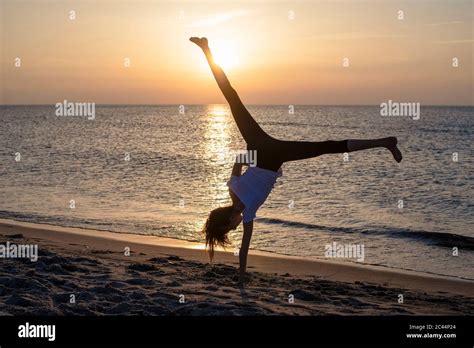 Silhouette Teenage Girl Making Handstand On Beach Sunset Hi Res Stock
