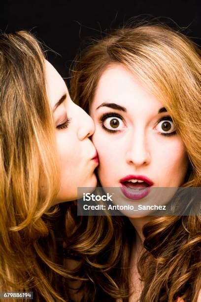 Two Beautiful Women Where One Of Them Is Giving A Kiss On The Cheek To The Other Over Black