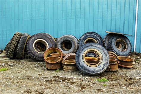 A Row Of Used Tires And Parts Sits With A Stack Of Rusty Old Rims In A