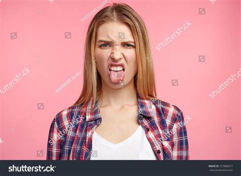 Dissatisfied Female Model Frowns Face Has Disgusting Expression Shows Tongue Expresses Non