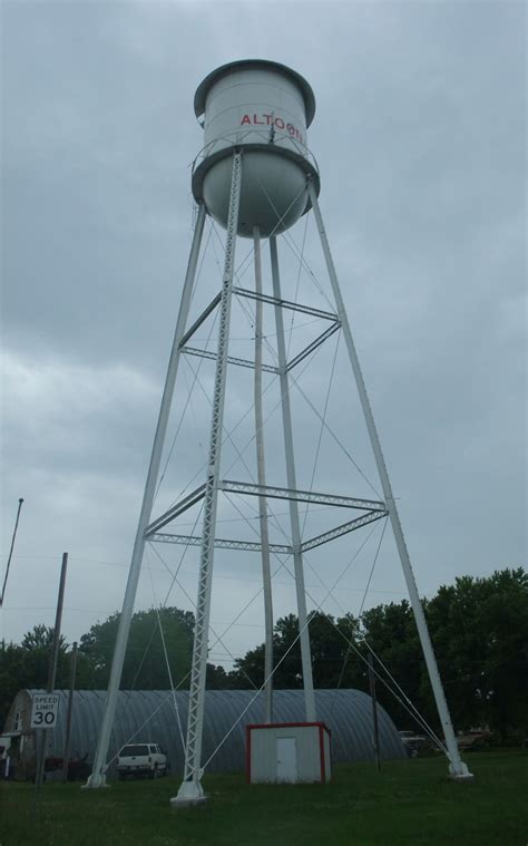 A Tall White Water Tower Sitting On Top Of A Lush Green Field