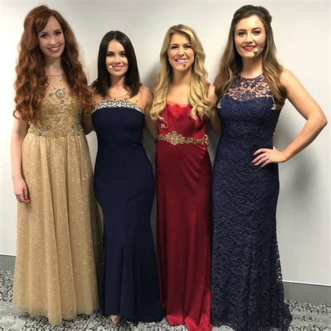 Three Women Standing Next To Each Other In Formal Dresses And One Is