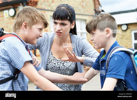 Teacher Stopping Two Boys Fighting In Playground Stock Photo Alamy